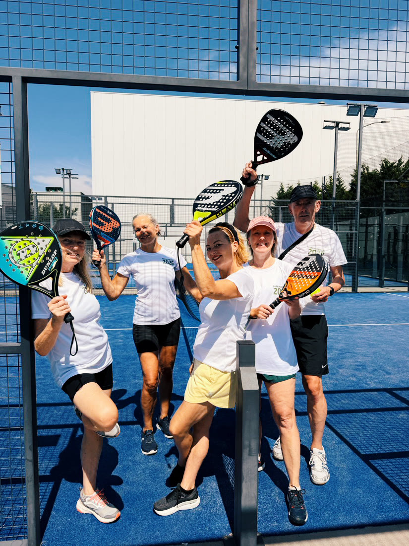 Spelers met hun rackets omhoog op de buitenbaan van Padel Mate Club